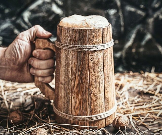 a person holding a wooden mug in their hand