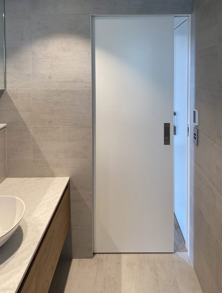 a bathroom with a sink and mirror next to a white door that leads to another room