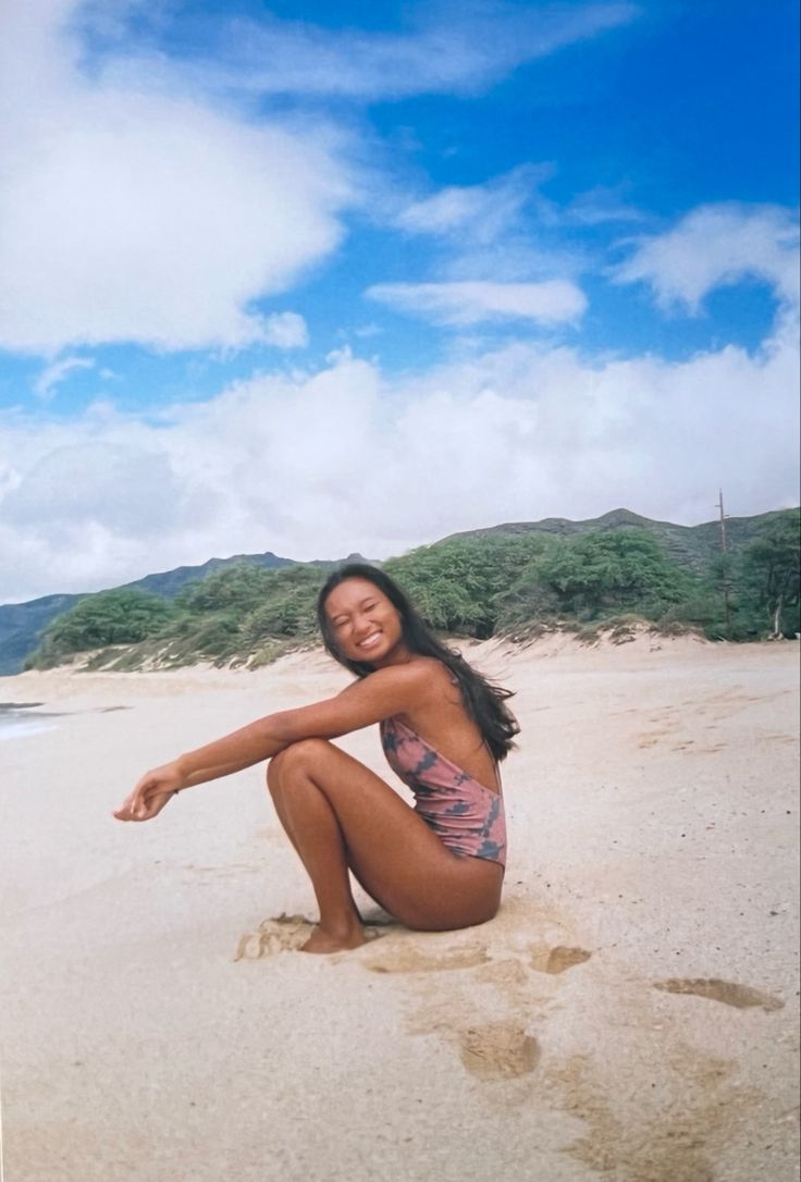 a woman sitting on top of a sandy beach