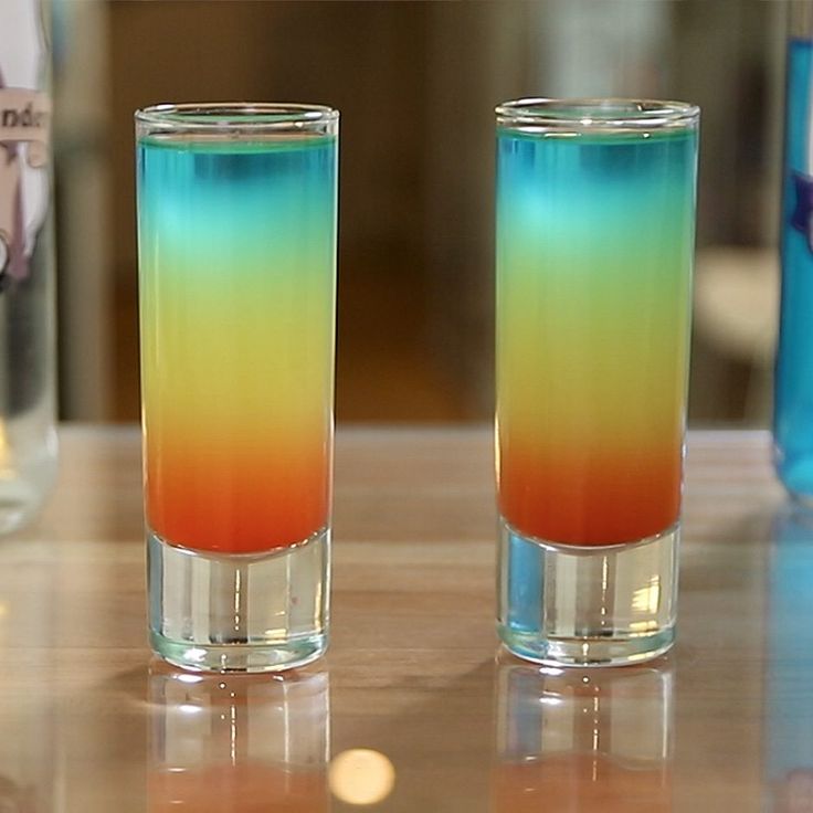 two glasses filled with colored liquid sitting on top of a table next to each other