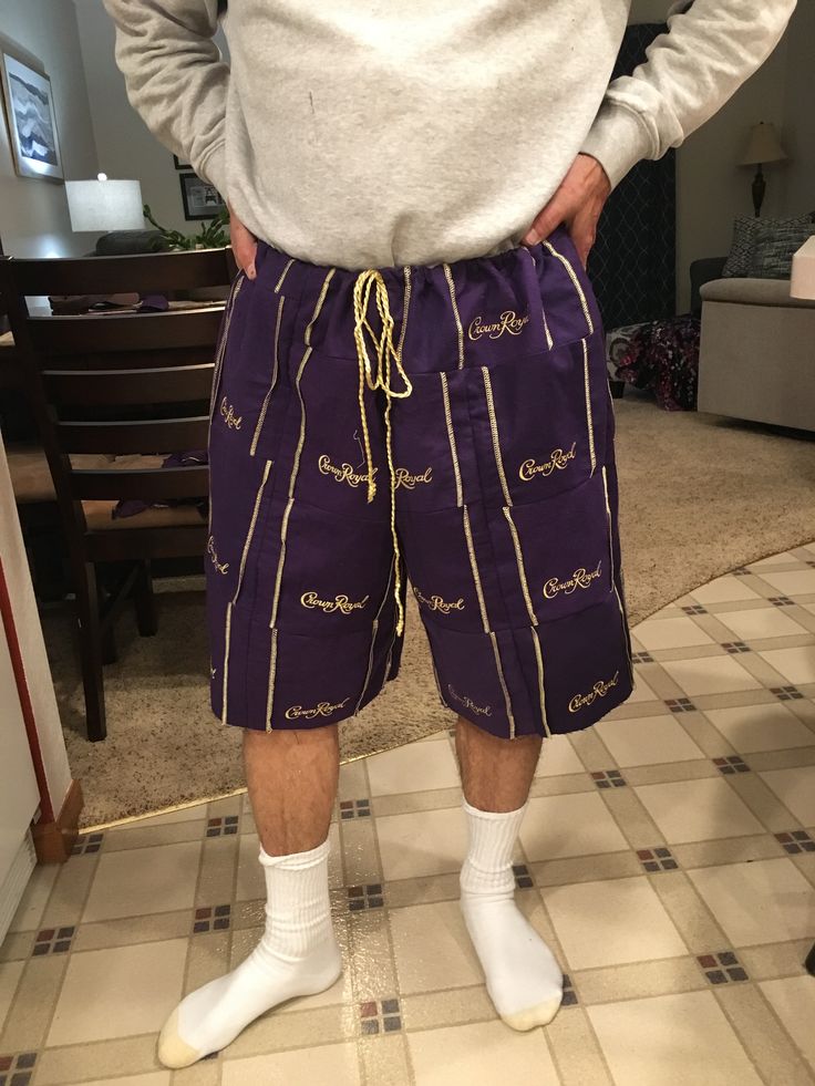 a man standing in front of a mirror wearing purple shorts and white socks with gold writing on them