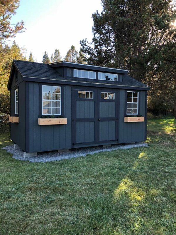 a small blue shed sitting on top of a lush green field