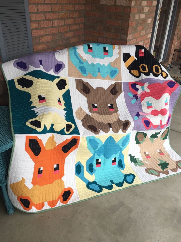 a quilted blanket with many different animal heads on it's side, sitting in front of a brick wall