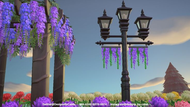 a street light with purple flowers hanging from it's sides and trees in the background