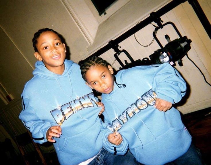 two children in matching blue sweatshirts posing for the camera