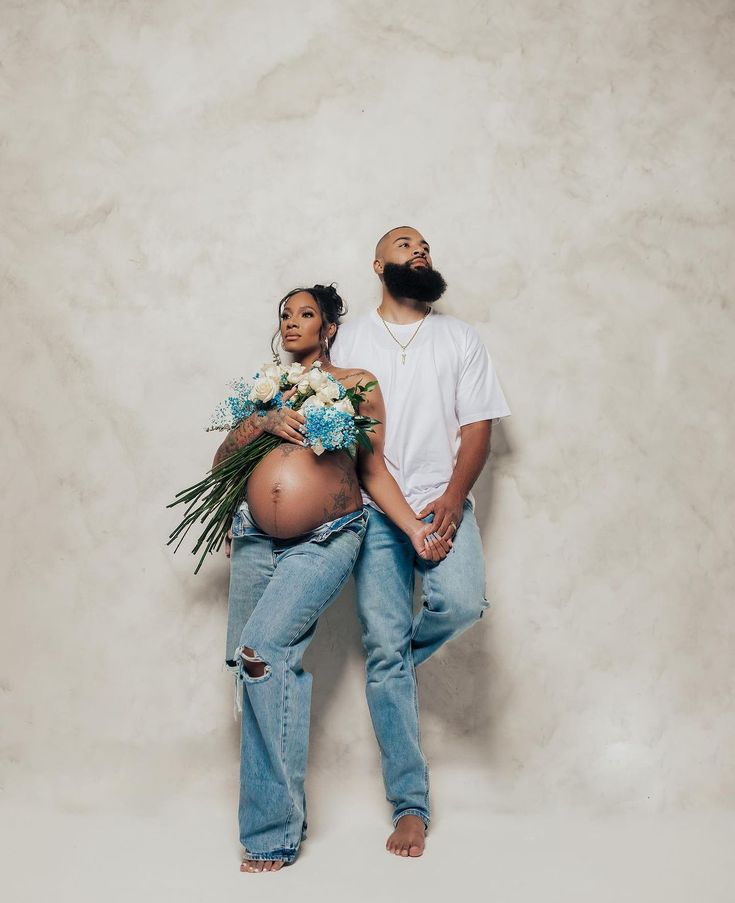 a pregnant woman sitting on top of a man's back with flowers in her lap