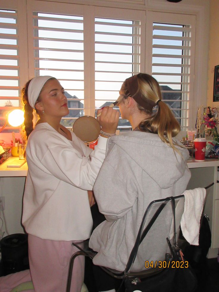 two women in white robes are brushing their teeth and looking at each other's eyes