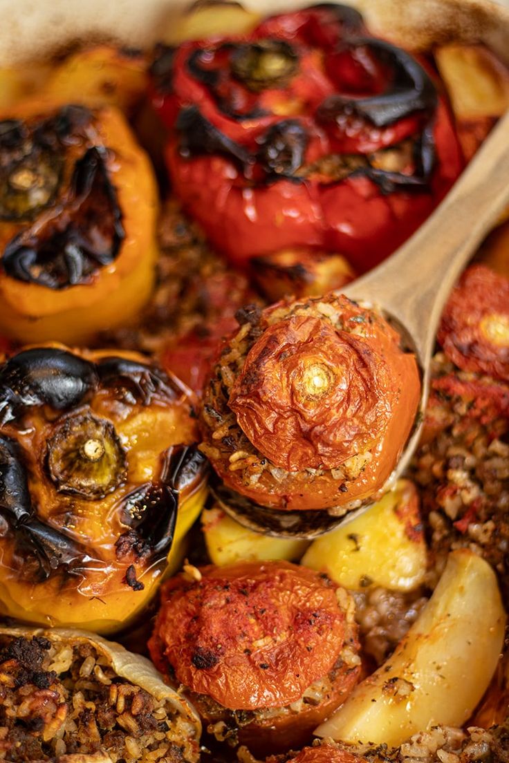 an assortment of stuffed peppers in a casserole dish with a wooden ladle