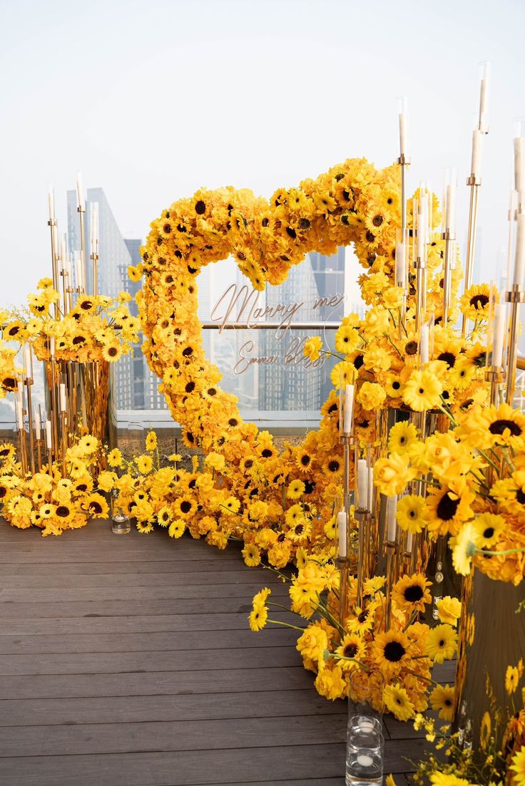 yellow flowers and candles are arranged in the shape of a heart on top of a building