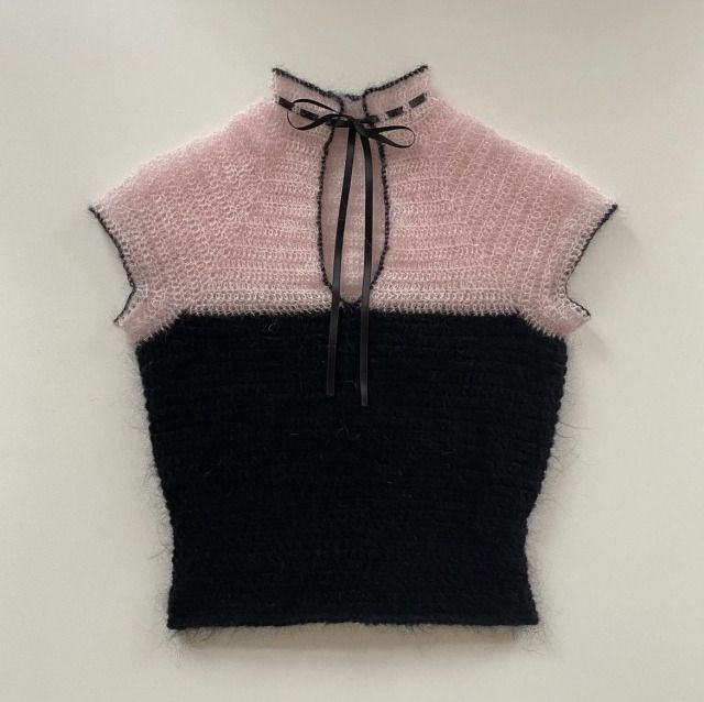 a black and pink sweater hanging on the wall with a tie around it's neck