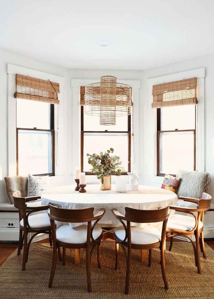 a dining room table surrounded by chairs and windows