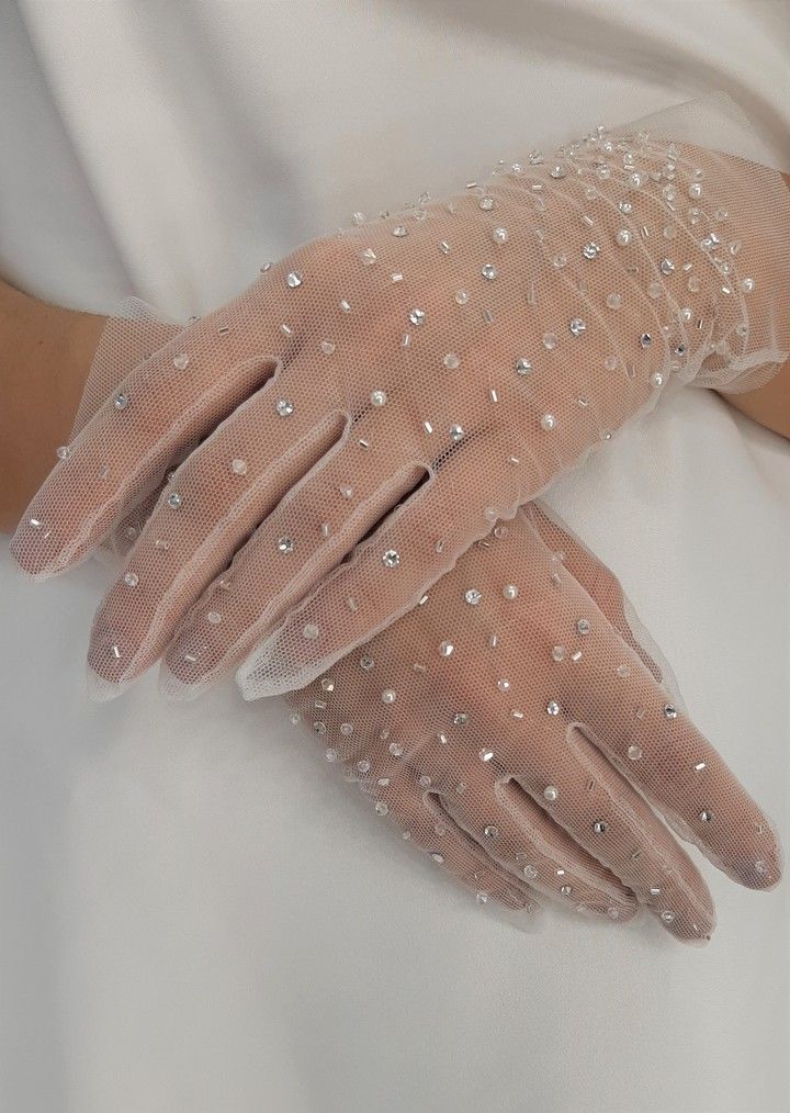 a pair of white gloves with pearls on the wrist and fingers are worn by a woman in a wedding dress