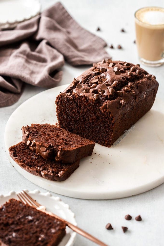 a piece of chocolate cake sitting on top of a white plate next to a cup of coffee