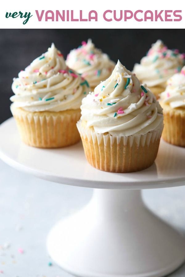 cupcakes with white frosting and sprinkles on a cake plate