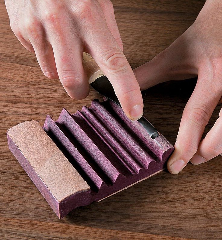 someone using a sharpener on a piece of purple paper with wood shavings