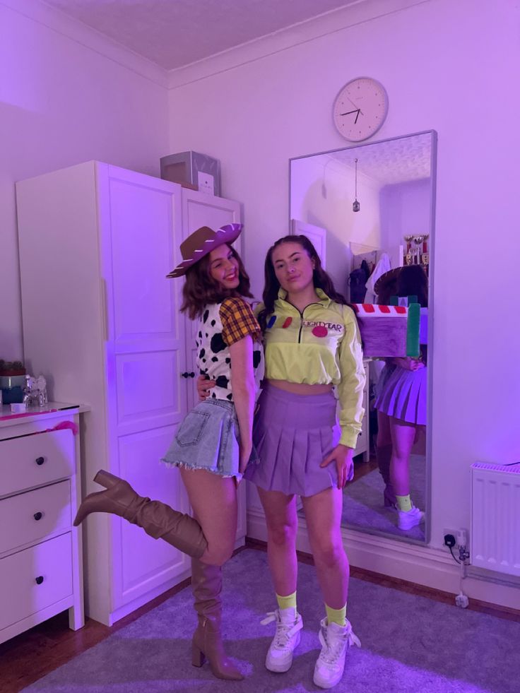 two young women standing in front of a mirror wearing short skirts and high heeled boots