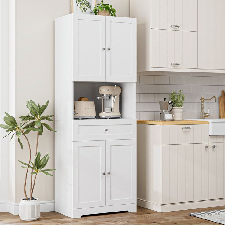 a kitchen with white cupboards and appliances next to a potted plant on the counter