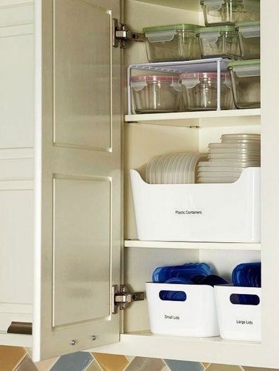 an open cabinet in a kitchen filled with dishes and containers on top of the cabinets