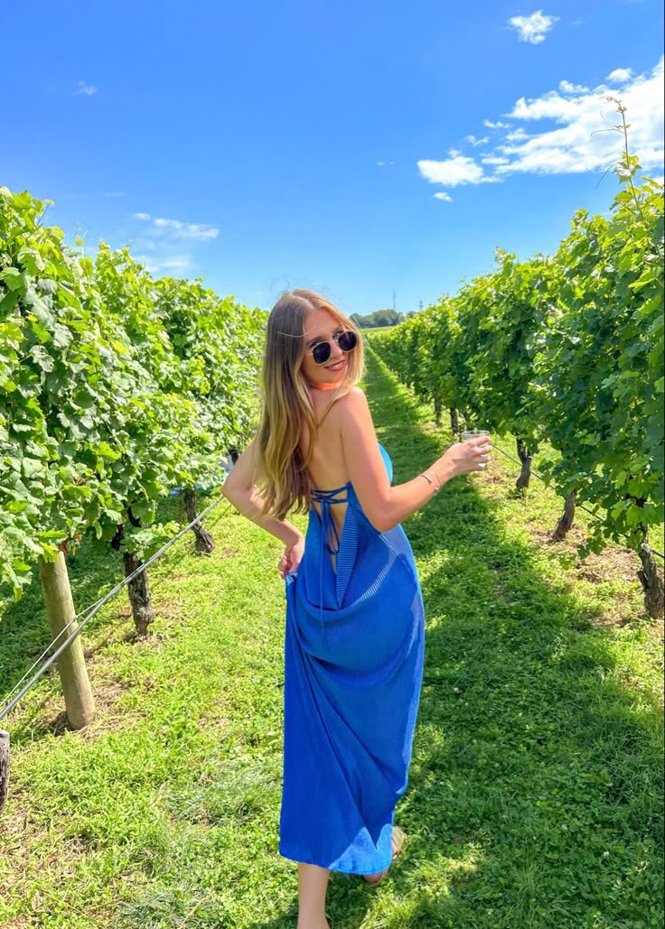 a woman standing in the middle of a vineyard