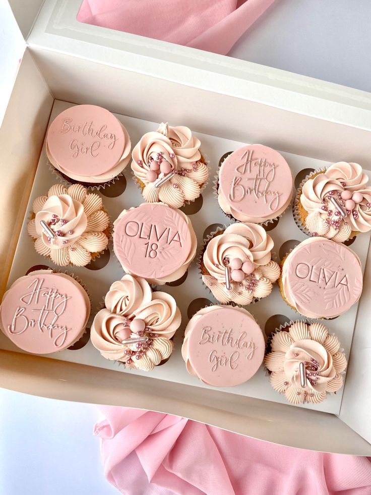 cupcakes in a box with pink frosting and flowers on the top one