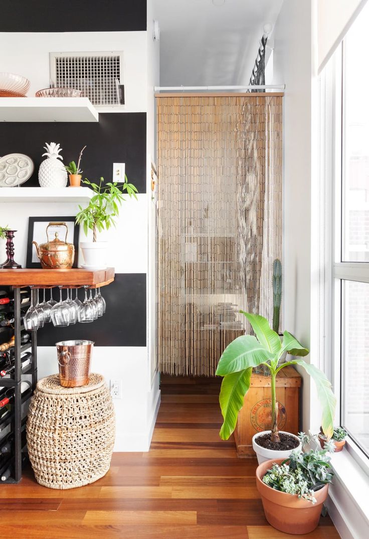 a room with wooden floors and shelves filled with pots, plants and wine bottles on top of the shelves