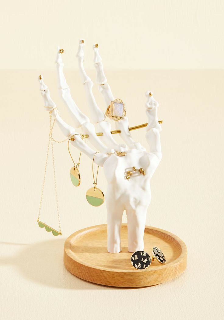 a white elephant figurine on a wooden base with jewelry hanging from it's back