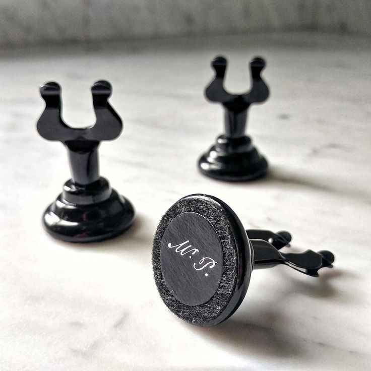 two black metal knobs with the word kr on them sitting on a white surface