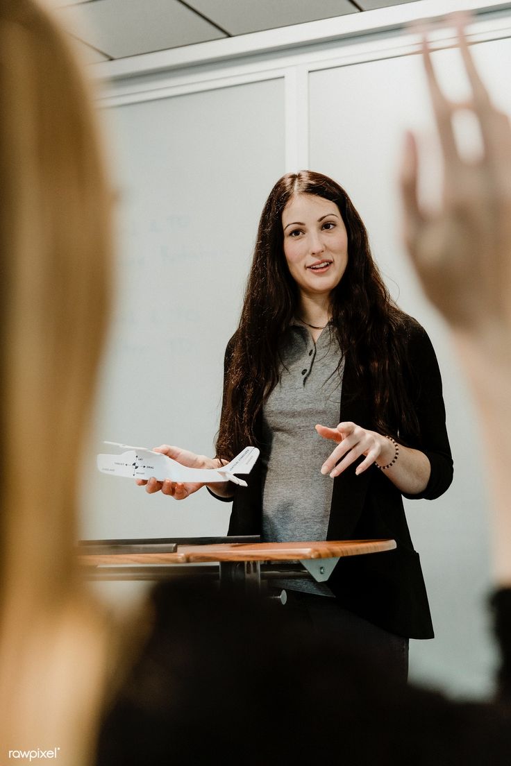 a woman standing in front of a whiteboard giving a presentation to someone behind her