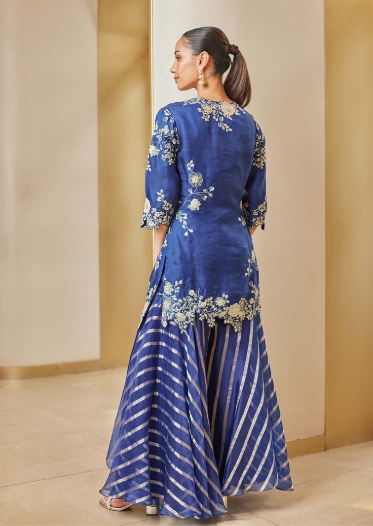 Editor's Note This is a stunning midnight blue sharara kurta set featuring intricate hand embroidery with applique-work, aari, and French knots. The embroidery work adds a touch of elegance and sophistication to the kurta and sharara, making it a perfect choice for any formal occasion or special event. The set includes a matching dupatta, completing the exquisite look. Fabric: Tissue Color: Blue Components: Kurta, sharara and dupatta Occasion: Festive and wedding guest Disclaimer: Product color Long Blouses, Blue Sharara, Kurta And Sharara Set, Kurta And Sharara, Neck Flower, Sharara Designs, Kurta Sharara, Lehnga Dress, Punjabi Dress