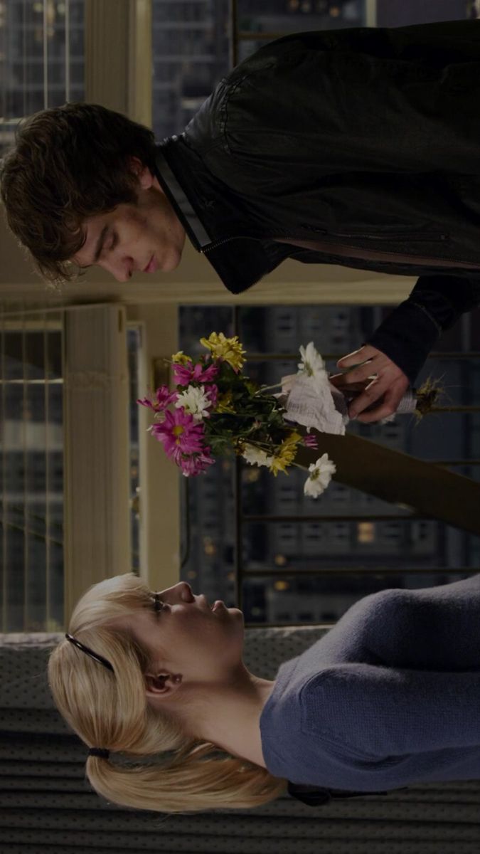 a man is giving flowers to a woman in front of a cityscape at night