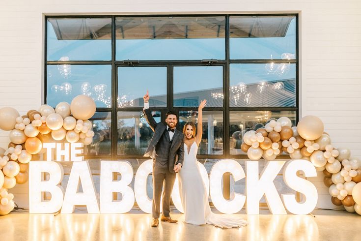 a bride and groom standing in front of the babocks sign at their wedding