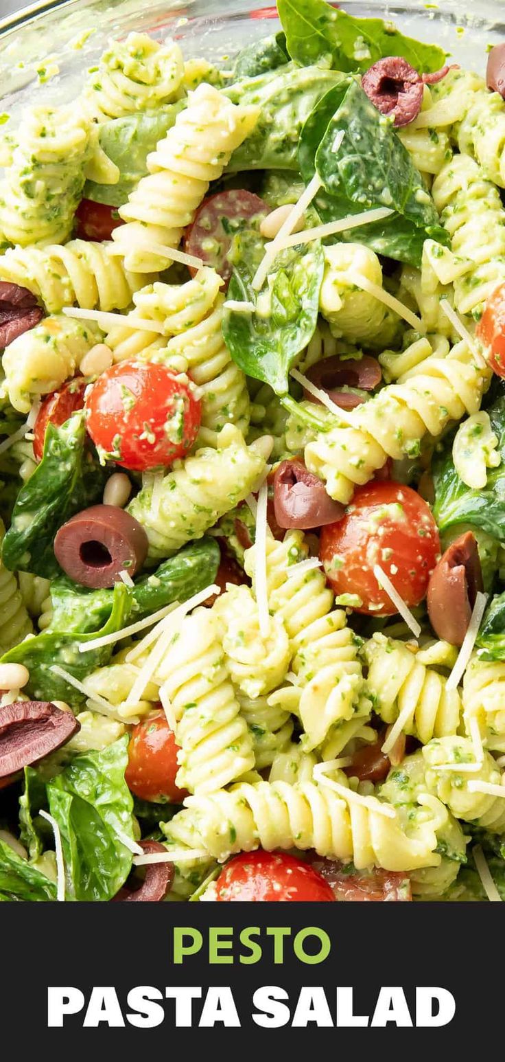 pasta salad with tomatoes, olives and lettuce in a glass bowl