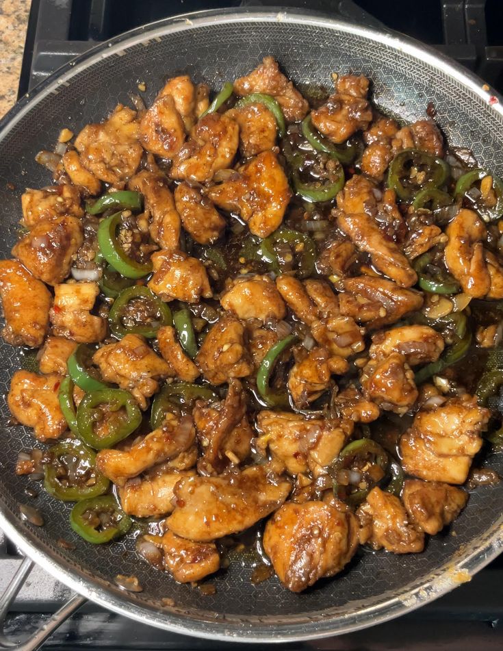 chicken and peppers are cooking in a skillet on the stove top, ready to be cooked