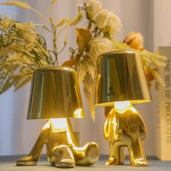 two gold elephant lamps sitting on top of a table next to a vase with flowers