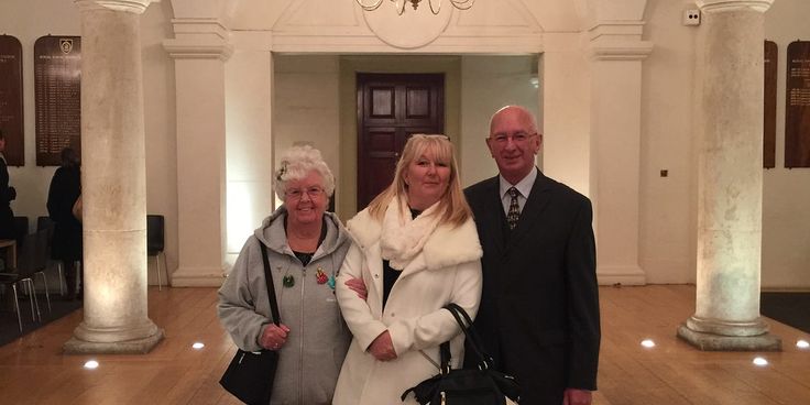 three people standing next to each other in a room with columns and chandeliers