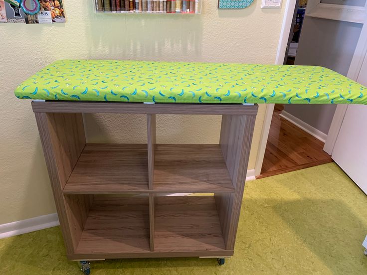 a green ironing board sitting on top of a wooden shelf