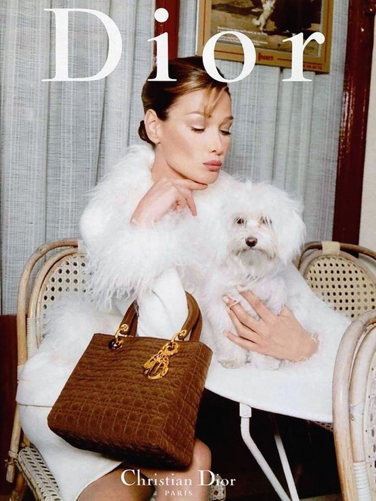 a black and white photo of a woman sitting at a table with a dog in her lap