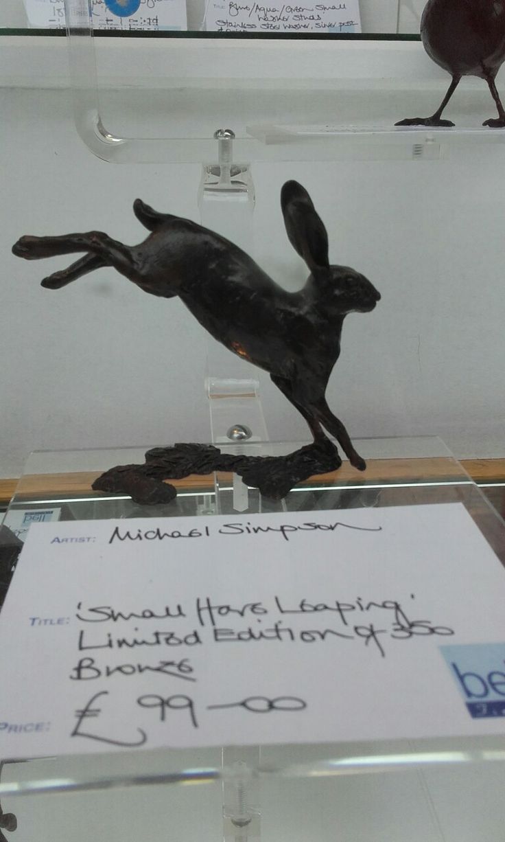 a statue of a running rabbit on display in a glass case with price tags attached to it