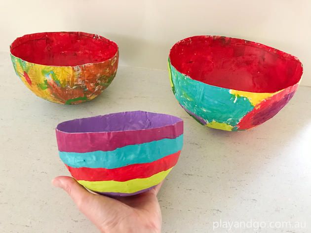 someone is holding two colorful bowls in their hand and another bowl has been made out of paper