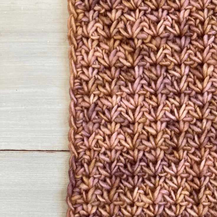 a crocheted piece of cloth sitting on top of a wooden table next to a pair of scissors