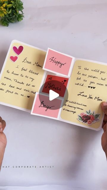 two hands holding an open book with writing on it and flowers in the back ground