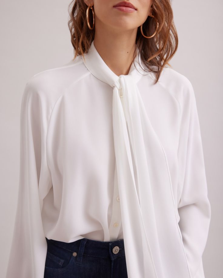 The SANTANA is a triacetate crepe shirt with long raglan sleeves, a single cuff with cufflink fastening. Knotted tie collar at the front. White Timeless Top With Relaxed Fit, Timeless White Relaxed Fit Top, Modern Office Shirt, Modern Stretch Tops For Formal Occasions, Modern Formal Stretch Tops, Timeless White Workwear Tops, Timeless White Tops For Workwear, Timeless White Tops For Work, Sleek White Formal Tops