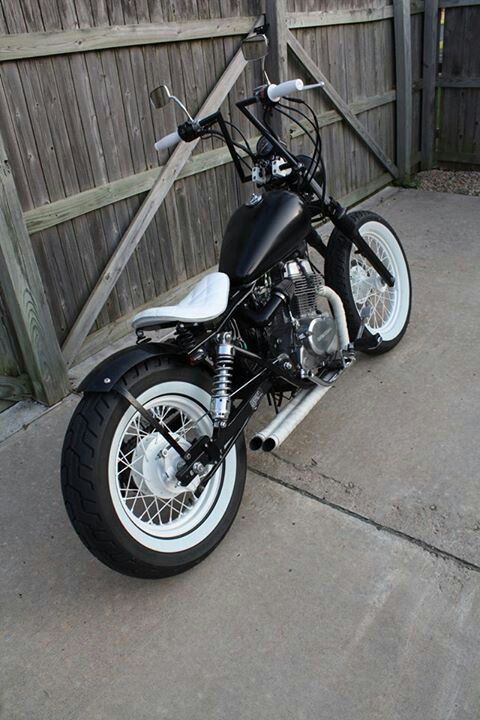 a black and white motorcycle parked next to a wooden fence