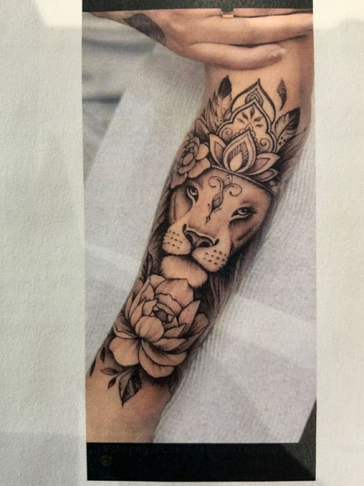 a woman with a lion tattoo on her arm and hand holding a flower in front of her face