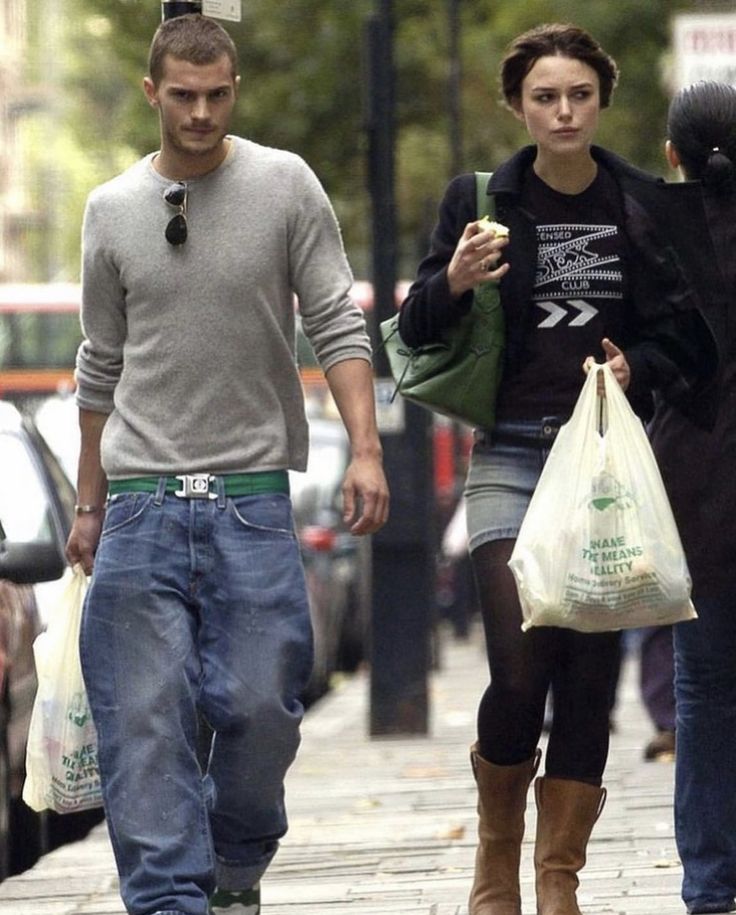 a man and woman walking down the street with bags in their hands, carrying groceries