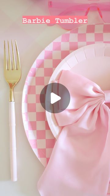 a pink and white plate with a bow on it next to a fork, knife and napkin