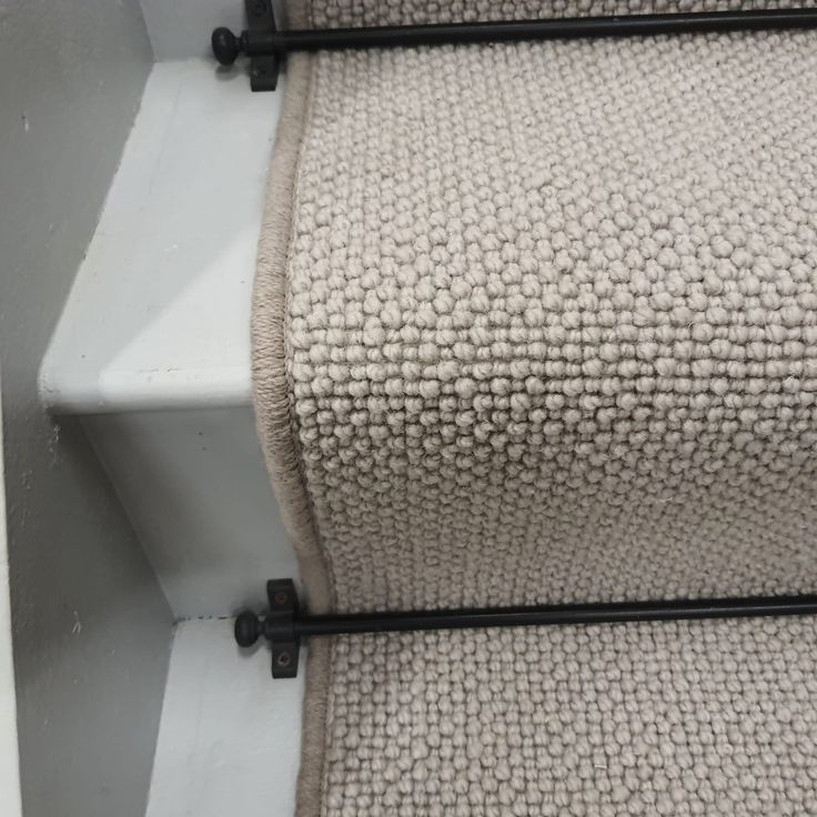 a close up view of a carpeted stair case with black metal bars on the bottom