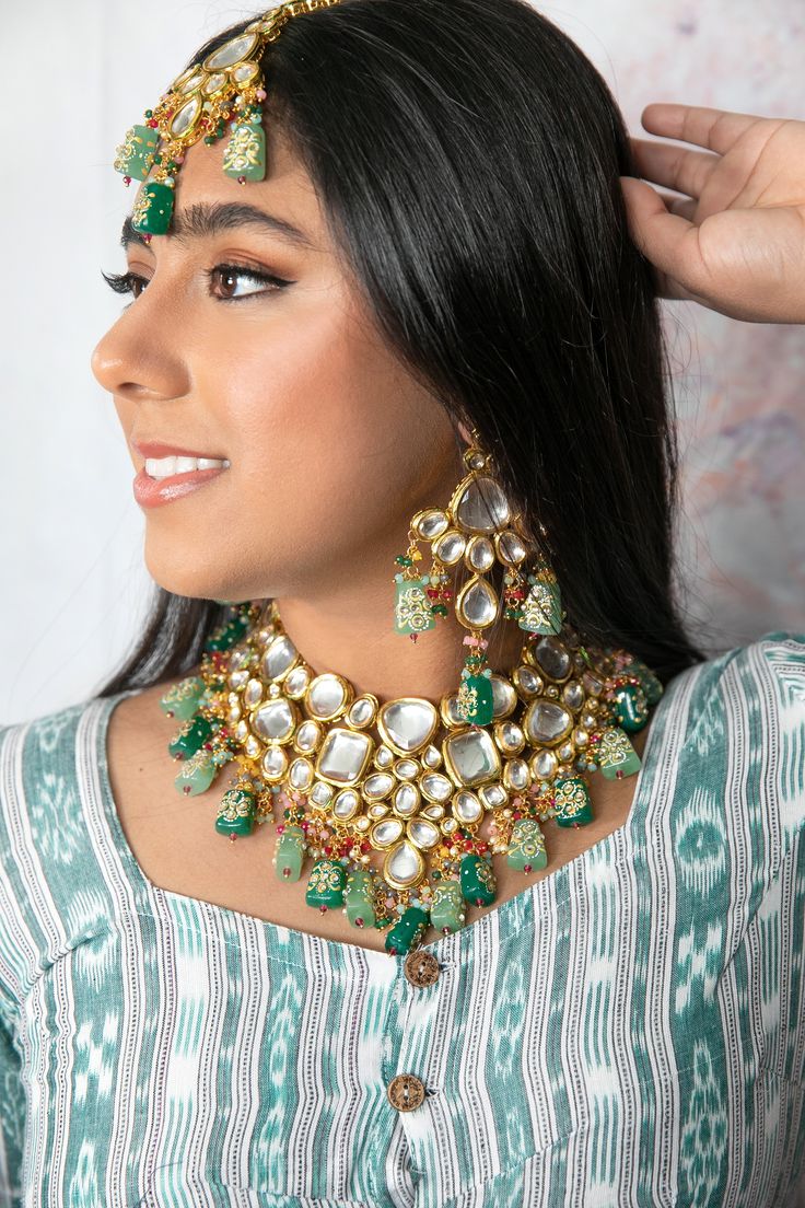 The Mahika Jewelry set is a handmade beauty. With its name meaning "earth" in Sanskrit this divine piece lives up to all expectations. Consisting of hand painted back meenakari, premium quality kundan, and mint and emerald handpainted Tanjore beads this lovely set is a must have in everyone's jewelry collection. Specifications Materials used: Kundan, Hand-painted Mint and Emerald Tanjore beads with back Hand-painted back Meenakari Weight: Necklace- 180 g, Earrings- 41.8 g, Tikka- 43.4 g At Romik Cheap Festive Meenakari Jewelry, Luxury White Meenakari Necklace, Luxury Spiritual Meenakari Necklace, Festive Green Kundan Necklace With Mirror Work, Traditional Jewelry With Mirror Work For Puja, Traditional Jewelry For Puja With Mirror Work, Green Kundan Jewelry With Meenakari, Green Kundan Necklace With Mirror Work For Festivals, Green Kundan Necklace With Mirror Work For Diwali