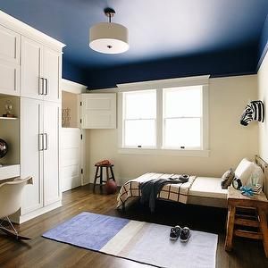 a bedroom with white cabinets and blue ceiling