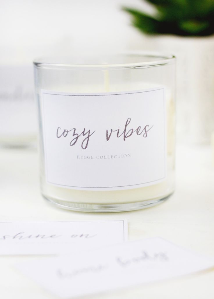 a white candle sitting on top of a table next to some cards and a potted plant